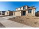 Two-story house with tan exterior, teal door, and landscaped yard at 18424 W Monte Lindo Ln, Surprise, AZ 85387
