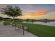Community lake with walking path, benches, and clubhouse under a colorful sky at 22788 E Orion Way, Queen Creek, AZ 85142