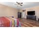 Bright bedroom with wood floors, a king-size bed, and a large TV at 7156 S Forest Ave, Gilbert, AZ 85298
