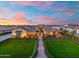 Aerial view showcasing a home's landscaped front yard, pristine lawn, and charming architectural details against a colorful sunset at 2652 E Pelican Ct, Gilbert, AZ 85297