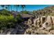 The exterior view of this house includes a waterfall, bridge, and lush greenery at 2233 E Behrend Dr # 210, Phoenix, AZ 85024
