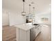 Kitchen island with white cabinets, quartz countertops and a stainless steel sink at 17798 W Coolidge St, Goodyear, AZ 85395