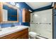 Well-lit bathroom featuring a vanity with a sink, wood cabinets, and a shower with glass doors at 3425 W Acoma Dr, Phoenix, AZ 85053