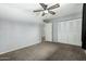 Bright bedroom featuring grey walls, carpeted floors, and a ceiling fan, creating a simple and comfortable living space at 3425 W Acoma Dr, Phoenix, AZ 85053