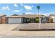 Charming single-story home with a well-manicured front yard, complemented by a white two-car garage and desert landscaping at 3425 W Acoma Dr, Phoenix, AZ 85053