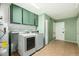 Practical laundry room with green walls, washer, dryer and storage cabinets at 3425 W Acoma Dr, Phoenix, AZ 85053