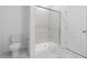 Bathroom featuring a glass-door shower, toilet, and updated marble tiling at 7552 W Park St, Laveen, AZ 85339