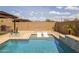 Up close view of backyard swimming pool with built in lounge chairs and beautiful desert landscaping at 10331 E Wavelength Ave, Mesa, AZ 85212