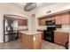 Classic kitchen with wood cabinetry, stainless steel refrigerator, kitchen island, and black appliances at 10209 W Jessie Ln, Peoria, AZ 85383
