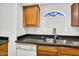 Close up of functional kitchen featuring gas range, dishwasher, and wood cabinets under natural light at 10030 W Indian School Rd # 218, Phoenix, AZ 85037