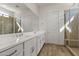 Bright bathroom featuring double sinks, large mirror and glass shower with tiled surround at 11691 N Luckenbach St, Surprise, AZ 85388