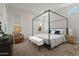 Bright bedroom with a modern four-poster bed, side tables, and a cozy seating area by the window at 11691 N Luckenbach St, Surprise, AZ 85388