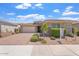 Charming single-story home with a well-manicured front yard and a brick driveway, under a bright blue cloudy sky at 28389 N 131St Dr, Peoria, AZ 85383
