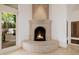 Unique curved fireplace with travertine surround and adjacent outdoor patio at 6620 E Stallion Rd, Paradise Valley, AZ 85253