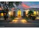 Elegant front entrance with an ornate gate, desert landscaping, and warm exterior lighting at twilight at 6620 E Stallion Rd, Paradise Valley, AZ 85253