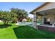 Lush backyard with a sparkling pool, waterfall feature, outdoor kitchen, covered patio, and synthetic grass at 1264 E Walnut Rd, Gilbert, AZ 85298