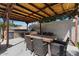 Outdoor kitchen under a pergola featuring a built-in grill, countertops, and dining space at 1264 E Walnut Rd, Gilbert, AZ 85298