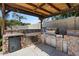 Well-equipped outdoor kitchen with a built-in grill and ample counter space beneath a wooden pergola at 1264 E Walnut Rd, Gilbert, AZ 85298