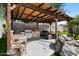 Outdoor kitchen with stainless grill and stone accents under pergola next to a waterfall feature at 1264 E Walnut Rd, Gilbert, AZ 85298