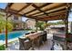 Outdoor living space under a wooden pergola with a built-in grill and dining area next to the pool at 1264 E Walnut Rd, Gilbert, AZ 85298