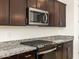 Modern kitchen with dark cabinets, granite countertops and stainless steel appliances at 36893 W La Paz St, Maricopa, AZ 85138
