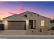 Charming single-story home with a well-manicured front yard and a two-car garage, illuminated by warm exterior lighting at 4958 W Hunter Trl, San Tan Valley, AZ 85144