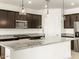 Modern kitchen with dark cabinetry, granite countertops, and a large island at 36914 W La Paz St, Maricopa, AZ 85138
