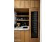 Elegant bar area with wood cabinets, marble countertop, sink, wine fridge, and stylish shelving at 9810 N 57Th St, Paradise Valley, AZ 85253