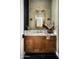 Stylish powder room features a wood vanity, marble countertop, decorative mirror, and designer light fixtures at 9810 N 57Th St, Paradise Valley, AZ 85253