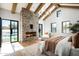 Spacious bedroom with stone fireplace, wood beam ceiling, and bright light from the pool patio at 9810 N 57Th St, Paradise Valley, AZ 85253