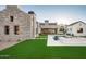An eye-level view of a backyard pool with a stone house exterior, lush lawn and landscaping at 9810 N 57Th St, Paradise Valley, AZ 85253