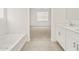 Bathroom featuring tiled floors, a tub, a dual sink vanity and open access to a bedroom at 20357 N 225Th Dr, Surprise, AZ 85387