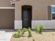 Close-up of the dark front door framed by desert landscaping and a stucco exterior, accentuating the home's charm at 20357 N 225Th Dr, Surprise, AZ 85387