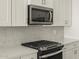Close-up showcasing the stainless steel microwave, stove, and gray tiled backsplash in this modern kitchen at 20357 N 225Th Dr, Surprise, AZ 85387