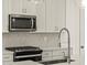 Contemporary kitchen featuring stainless steel appliances, white cabinets, and a gray tiled backsplash at 20357 N 225Th Dr, Surprise, AZ 85387