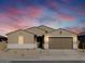 Tan two-story house with brown garage door, landscaping, and a twilight sky at 36954 W La Paz St, Maricopa, AZ 85138