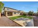 Expansive backyard featuring a covered patio, green grass, fire pit, desert landscaping, and block fence at 14829 W Pershing St, Surprise, AZ 85379