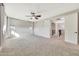 Carpeted bedroom with ceiling fan, window with sheer curtains, and access to hallway at 14829 W Pershing St, Surprise, AZ 85379