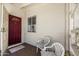 Inviting front porch featuring a red entry door, two chairs with cushioned pillows, and neutral decor at 11038 W Windsor Dr, Sun City, AZ 85351