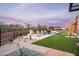 A backyard with a pool, spa, artificial turf, and a stone outdoor kitchen with pergola at 8386 E Leaning Rock Rd, Scottsdale, AZ 85266