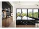 Modern bar area with black marble countertop and wood cabinets against black accent wall and large picture window at 8386 E Leaning Rock Rd, Scottsdale, AZ 85266