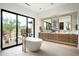 Bright bathroom featuring a soaking tub, dual vanities, and a view of the outdoors at 8386 E Leaning Rock Rd, Scottsdale, AZ 85266