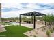 Outdoor kitchen and dining area with a grill, bar, and turf grass by the pool and spa at 8386 E Leaning Rock Rd, Scottsdale, AZ 85266