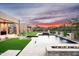 Expansive pool area with modern water features, elegant travertine decking, and artificial turf at 8386 E Leaning Rock Rd, Scottsdale, AZ 85266