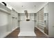 Spacious walk-in closet with white custom shelves, wooden rods, hardwood flooring, and central island at 8386 E Leaning Rock Rd, Scottsdale, AZ 85266