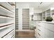 Large walk-in closet with white custom shelves, wooden rods, hardwood flooring, and full-length mirrors at 8386 E Leaning Rock Rd, Scottsdale, AZ 85266