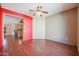 Bedroom with red and beige walls, hardwood floors, and view to dining area at 19403 N Ponderosa Ct, Surprise, AZ 85387