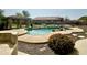 Backyard pool with rock waterfall feature, beautiful landscaping, and covered patio area at 9827 W Keyser Dr, Peoria, AZ 85383