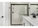 A stylish bathroom with a glass shower door, marble tiling, and black fixtures at 5678 N 205Th Ln, Buckeye, AZ 85396