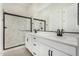 A bright bathroom showcasing dual vanities, a large mirror, and a sleek glass-enclosed shower at 5678 N 205Th Ln, Buckeye, AZ 85396